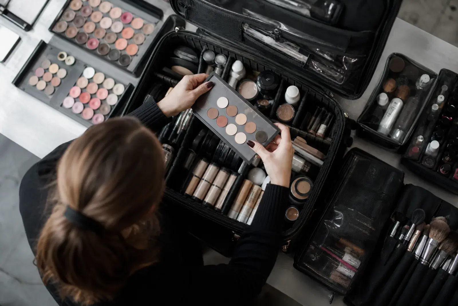 Freelance makeup artist packing a professional kit with depotted palettes